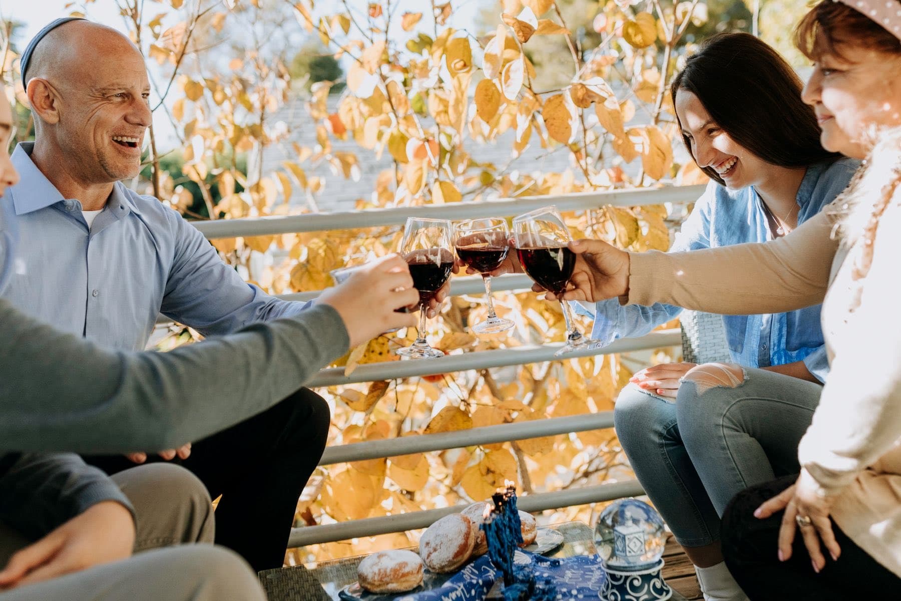 Family toasting with red wine on a sunny porch in autumn