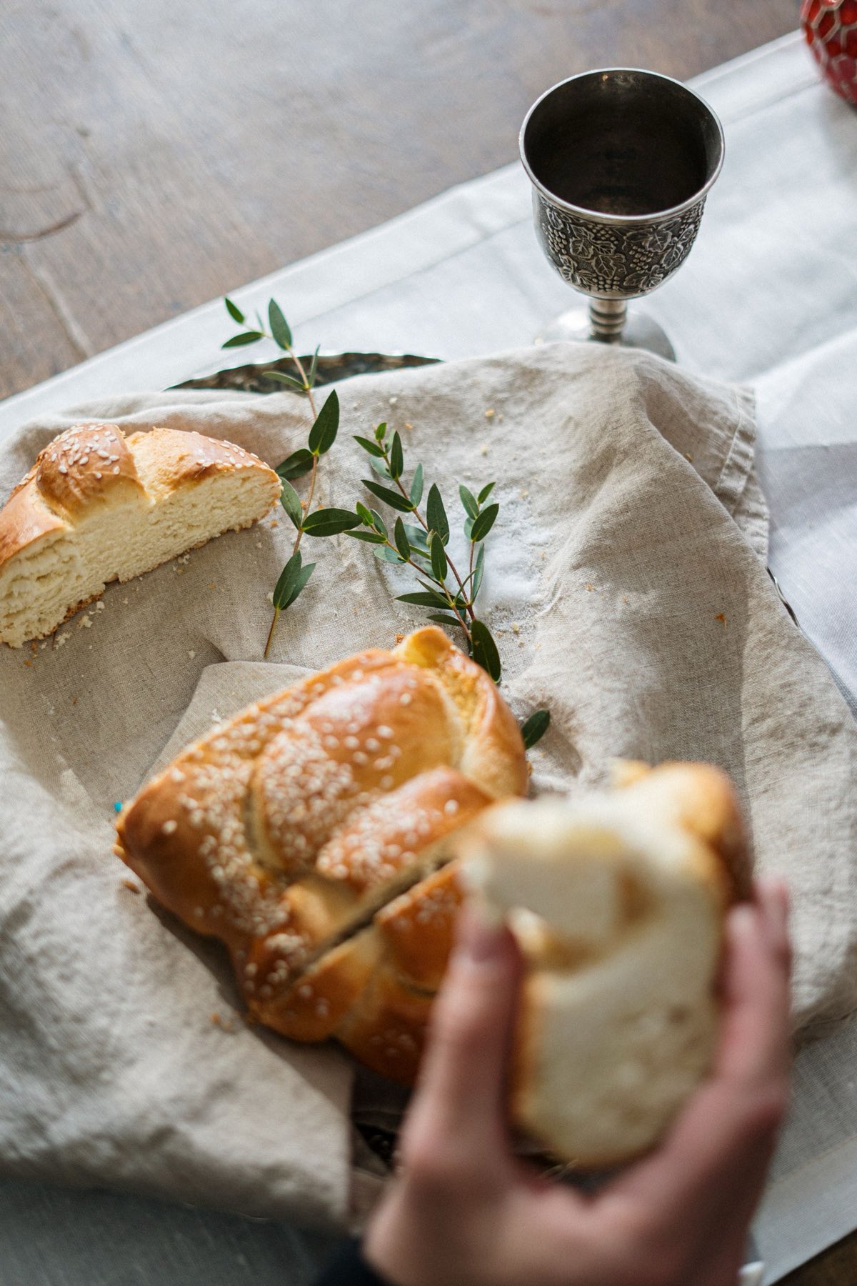 Braided challah and a silver kiddush cup on a linen cloth